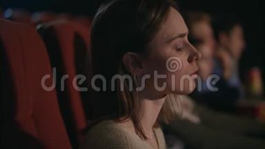 年轻女孩在电影院仔细地看电影。 电影里漂亮的女人脸